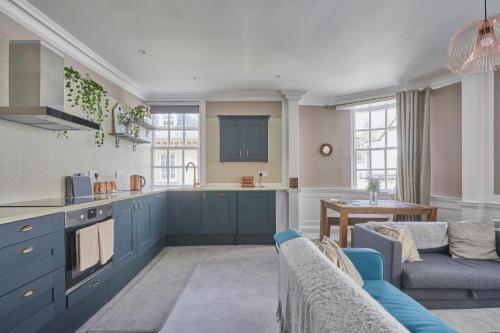 a kitchen and living room with blue cabinets and a couch at Superhost UK, FREE Parking, Fireplace, Bath City Center Luxury Maisonette! in Bath