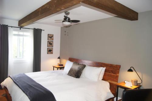 a bedroom with a white bed with a ceiling fan at Restaurant et Gite Les Passionnés in Val-David