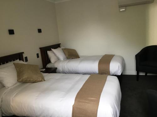 a hotel room with two beds and a chair at The Stables Dunedin in Dunedin