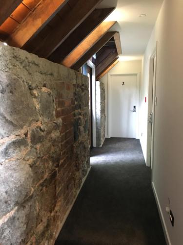 an empty hallway with a stone wall and a white door at The Stables Dunedin in Dunedin