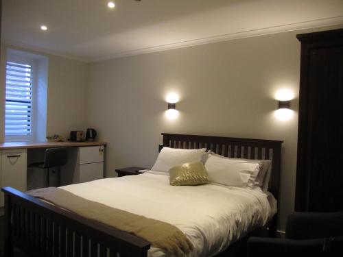 a bedroom with a bed with white sheets and pillows at The Stables Dunedin in Dunedin