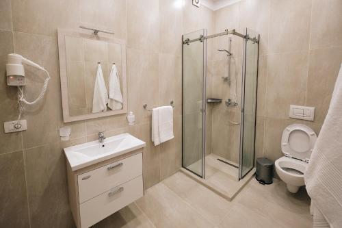 a bathroom with a shower and a sink and a toilet at In Center Hotel in Tirana