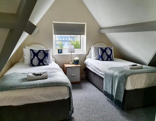 two beds in a attic room with a window at The Hedley Townhouse in Bournemouth