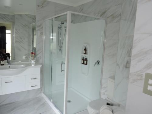 a white bathroom with a shower and a sink at 5 Acres B&B in Tokoroa