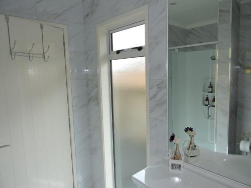 a white bathroom with a shower and a mirror at 5 Acres B&B in Tokoroa