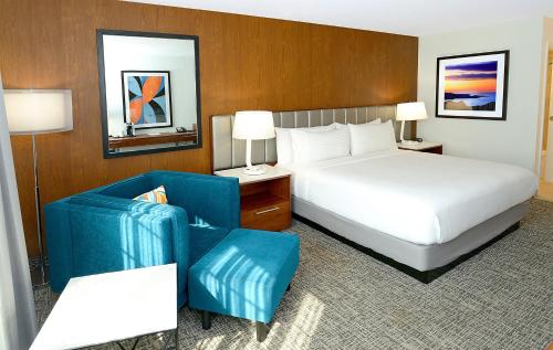 a hotel room with a bed and a blue chair at Holiday Inn & Suites San Mateo - SFO by IHG in San Mateo