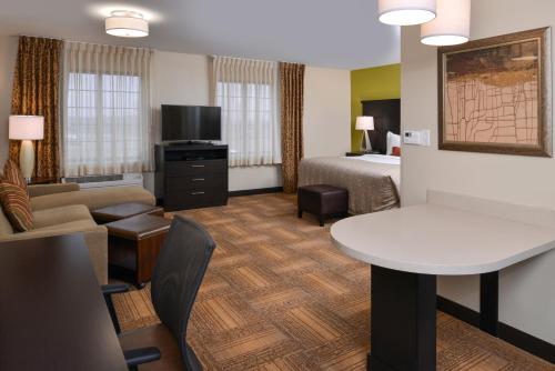 a hotel room with a bed and a table at Staybridge Suites Merrillville by IHG in Merrillville