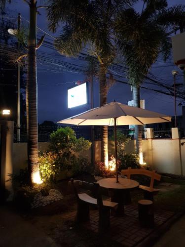 a table and chairs with an umbrella and palm trees at night at JPrime Apartelle in Tuguegarao City