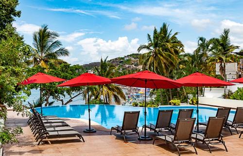 una piscina con sedie e ombrelloni rossi di Hotel Ysuri Sayulita a Sayulita