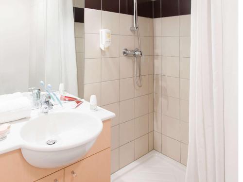 a bathroom with a sink and a shower at Aparthotel Adagio Access Saint Louis Bâle in Saint-Louis