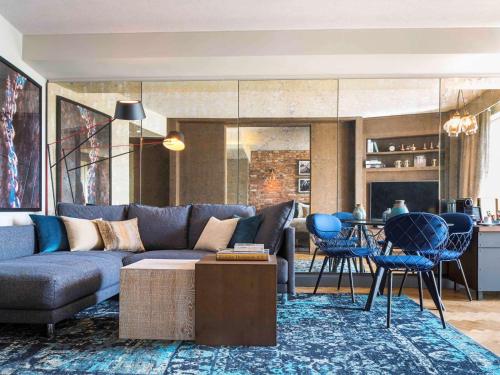 a living room with a blue couch and a table at Novotel London Canary Wharf in London