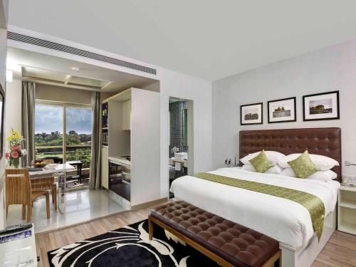 a bedroom with a large bed and a dining room at Grand Mercure Vadodara Surya Palace in Vadodara