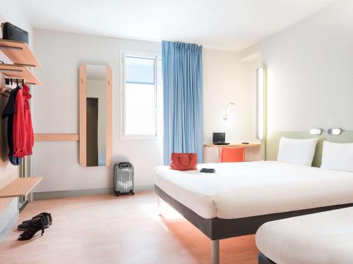 a hotel room with two beds and a mirror at ibis Budget Bobigny Pantin in Bobigny