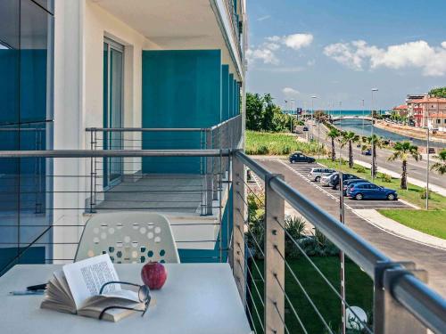 a balcony with a table with a book and an apple at Hotel Viareggio in Viareggio