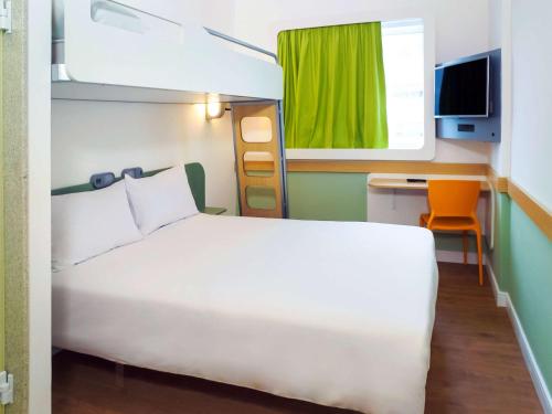 a bedroom with a white bed and a green window at ibis budget Osasco in Osasco