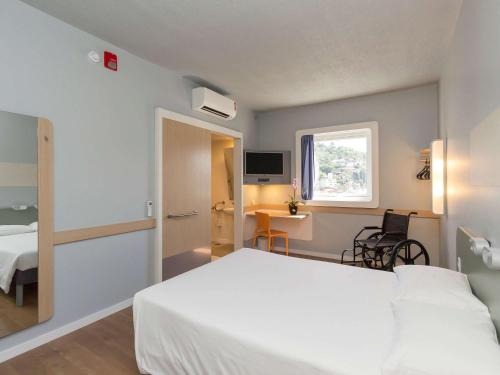 een hotelkamer met een wit bed en een bureau bij ibis budget Blumenau in Blumenau