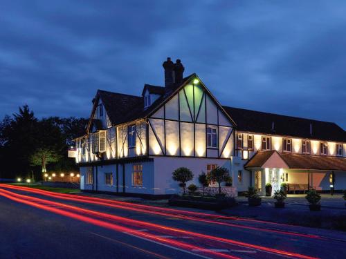 a large white house with lights on it at night at Mercure Thame Lambert Hotel in Chinnor