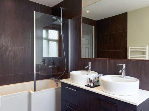 a bathroom with two sinks and a large mirror at Mercure Thame Lambert Hotel in Chinnor