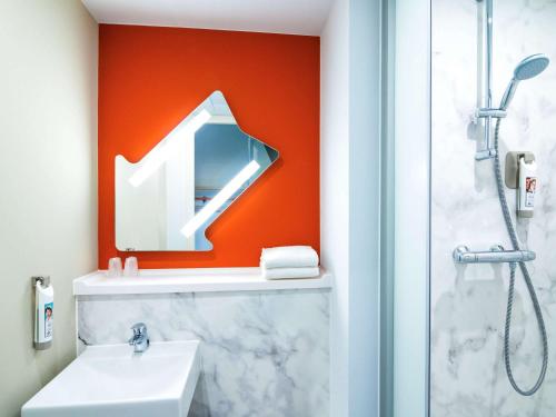 ein Bad mit einem Waschbecken, einem Spiegel und einer Dusche in der Unterkunft ibis budget Rotterdam The Hague Airport in Rotterdam