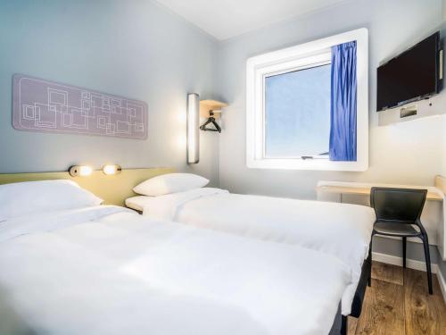 two beds in a room with a window and a chair at ibis budget Calama in Calama