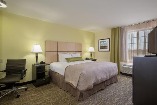 Del CityにあるCandlewood Suites Del City, an IHG Hotelのベッド、デスク、椅子が備わるホテルルームです。