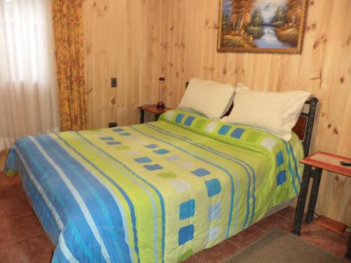 sypialnia z łóżkiem z żółtym i niebieskim kocem w obiekcie Hostal Emalafquen w mieście Pucón