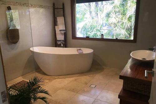 Byron Bay hinterland house - amazing sunset views! في Myocum: حمام مع حوض ومغسلة ونافذة