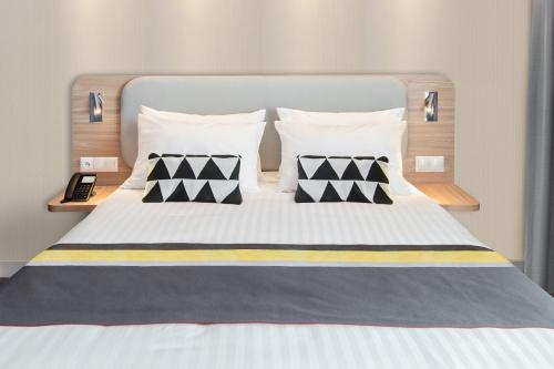 a bed with black and white pillows on it at Holiday Inn Express - Rzeszow Airport by IHG in Rzeszów