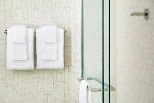 Holiday Inn Express & Suites Clear Spring, an IHG Hotel في Clear Spring: حمام به مناشف بيضاء معلقة على الحائط