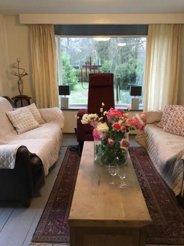 un soggiorno con un vaso di fiori su un tavolino da caffè di Cornerhouse nr 75 a Heijen