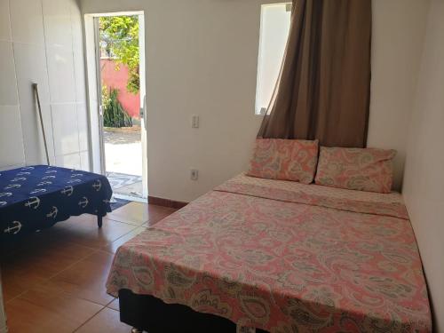 1 dormitorio con 1 cama y puerta corredera de cristal en Quitinetes e Suites em Arraial, en Arraial do Cabo