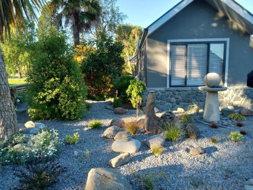 a garden with rocks and a small house at Four Peaks Motel in Geraldine