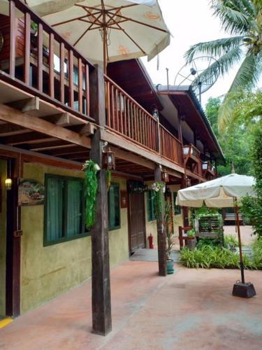 a patio with an umbrella and a building at Chuchaiburi Sri Amphawa in Amphawa