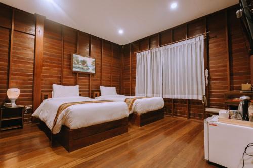 two beds in a room with wood paneled walls at Chuchaiburi Sri Amphawa in Amphawa