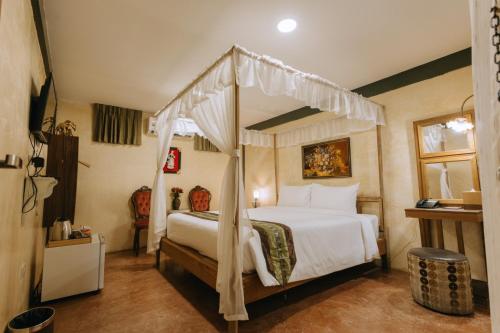 a bedroom with a bed with a canopy at Chuchaiburi Sri Amphawa in Amphawa