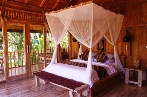 a bedroom with two beds in a room with windows at Kidem Ubud Villas in Ubud