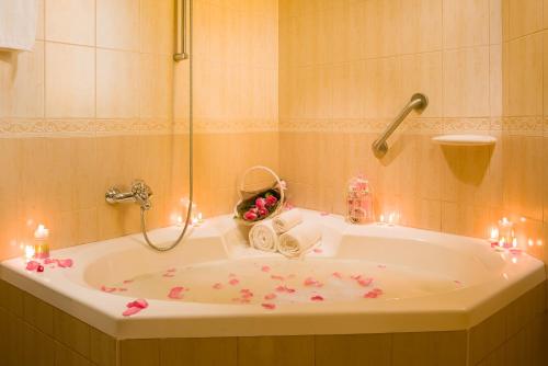 uma casa de banho com uma banheira com flores cor-de-rosa em Masira Island Resort em Ḩilf