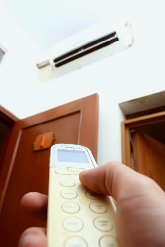 a hand holding a remote control in front of a room at Unique Guesthouse in Bandung