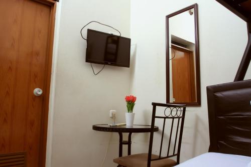 a small table with a chair and a tv on a wall at Unique Guesthouse in Bandung