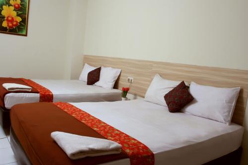 two beds in a hotel room with red and white pillows at Bantal Guling Trans in Bandung
