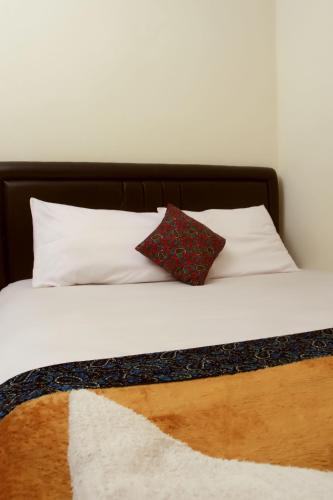 a bed with white sheets and a red pillow on it at Bantal Guling Trans in Bandung