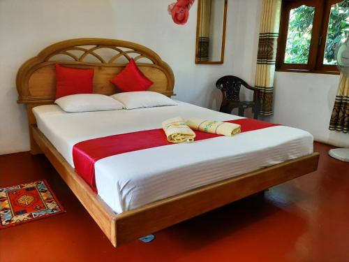 1 dormitorio con 1 cama grande con almohadas rojas en Lalanga Homestay, en Kandy