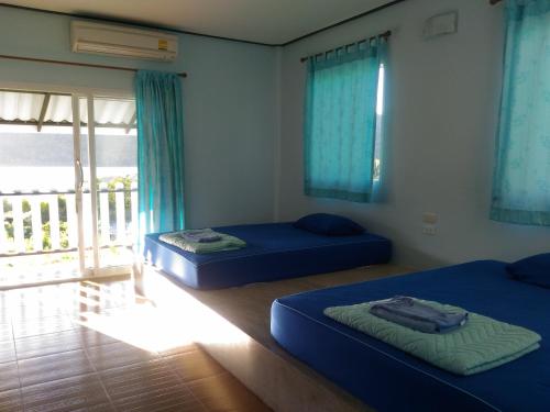 two beds in a room with blue sheets and a window at Ao Salat View Koh Kood in Ko Kood
