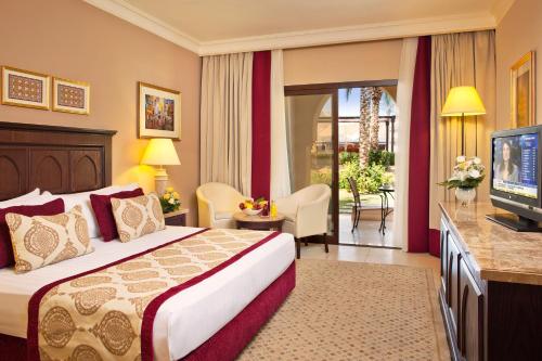 a hotel room with a bed and a television at Miramar Al Aqah Beach Resort in Al Aqah