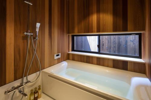 a bath tub in a bathroom with a window at Gion Minami Banka Machiya House in Kyoto