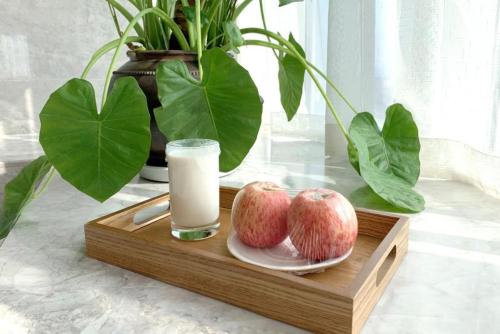 a wooden tray with two apples and a glass of milk at Bai Yun Qin She Boutique in Chongqing