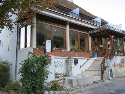 a white house with glass windows and stairs at Hotel Restaurant Le Traineau in Clelles