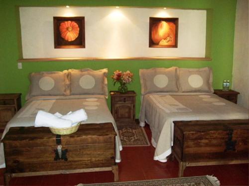 two beds in a room with green walls at Casa Limonchelo Hotel B&B in Morelia