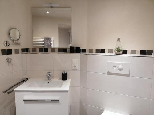 uma casa de banho branca com um lavatório e um espelho em Ferienwohnungen Blum em Kelberg