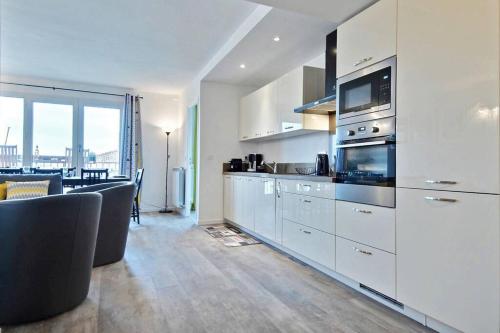 une cuisine avec des placards blancs et une salle à manger dans l'établissement Le Grand Joliette Marseille 